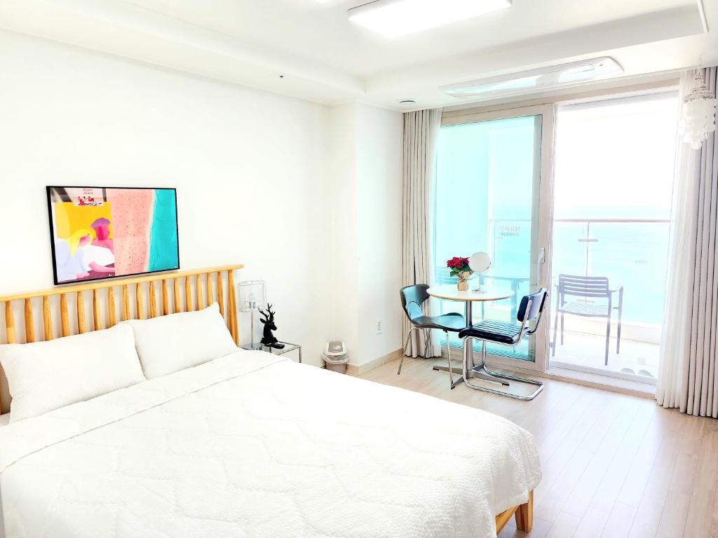 a white bedroom with a bed and a table with chairs at Sokcho Summitbay 1709 "Panoramic Ocean View" in Sokcho