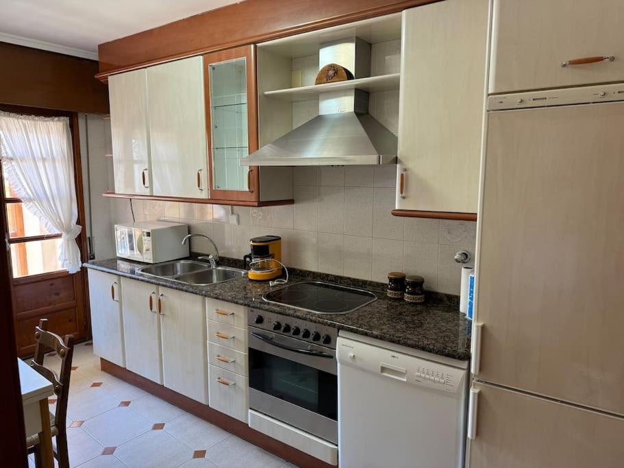een keuken met witte kasten, een wastafel en een koelkast bij Casa de pueblo in Samaniego