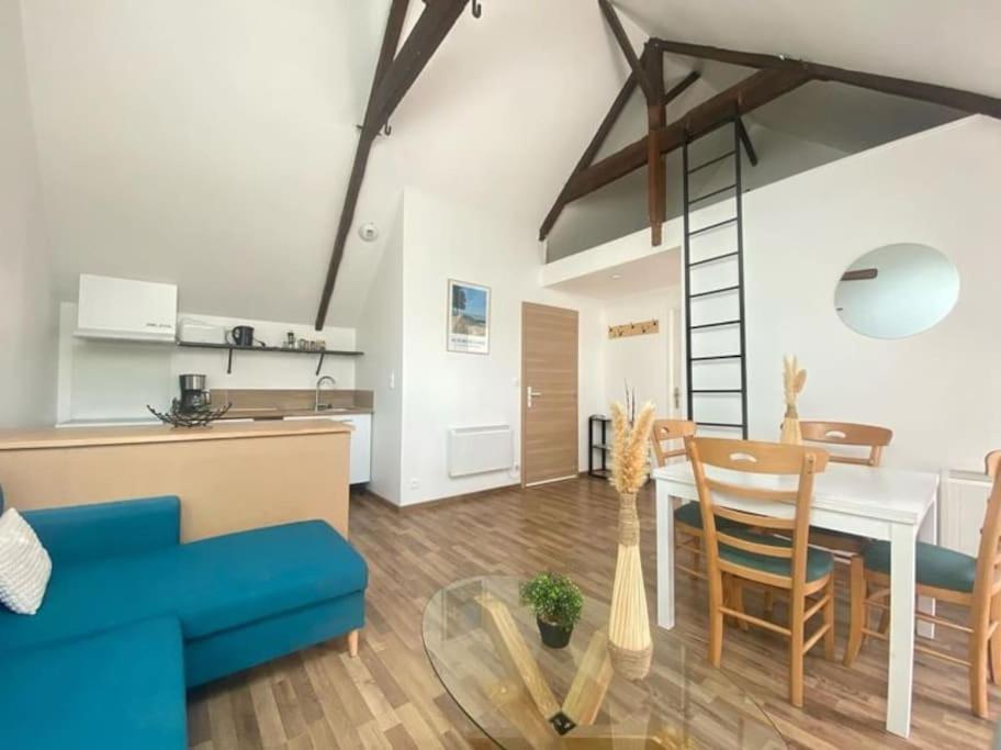 ein Wohnzimmer mit einem blauen Sofa und einem Tisch in der Unterkunft Au bord de mer in Saint-Benoît-des-Ondes