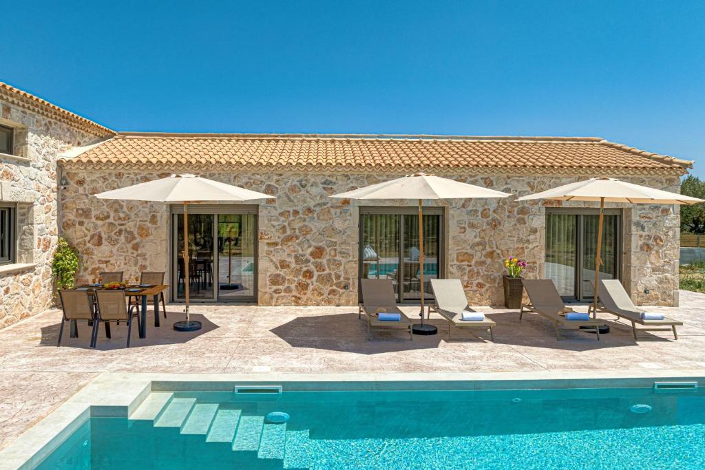 a villa with a pool and chairs and umbrellas at Villa Nava - Nestled in Olive Trees with Private Pool, by ZanteWize in Alykes
