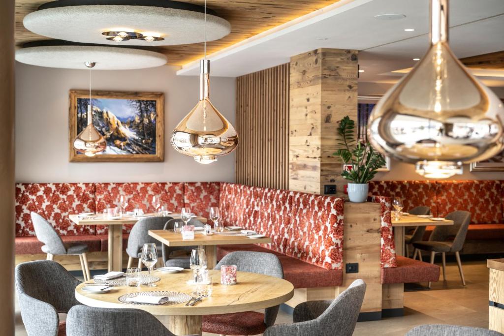 a restaurant with tables and chairs and chandeliers at Ciampedie Luxury Alpine Spa Hotel in Vigo di Fassa