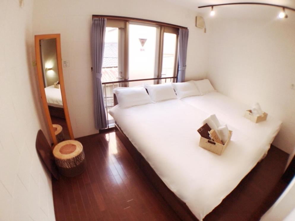 a bedroom with a large white bed with a window at Osaka Sinsei Guest House in Osaka