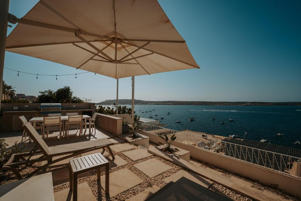 a patio with a table and an umbrella and the water at Beachfront Luxury Villa in Mellieħa