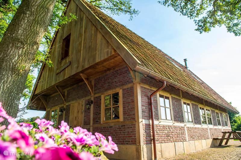 a small brick house with a tree and pink flowers at Erve Schuurboer in Tilligte
