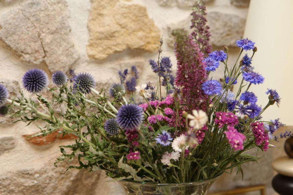 a glass vase filled with purple and purple flowers at Aux Pierres Magiques in Saint-Laurent-de-Chamousset