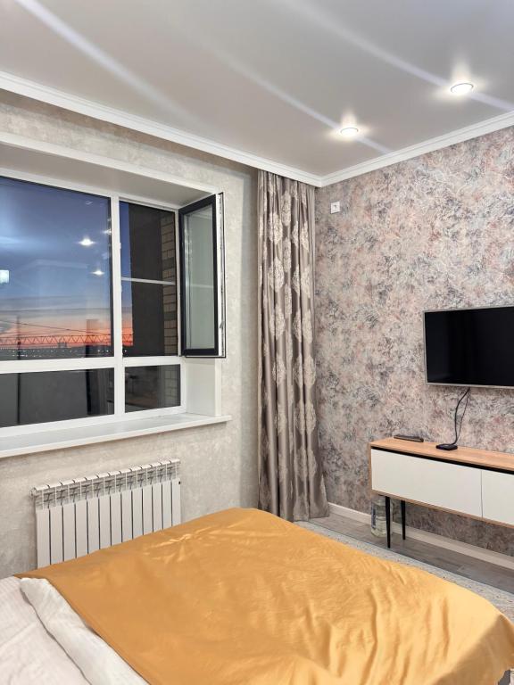 a bedroom with a bed and a flat screen tv at Dastur in Taldykolʼ