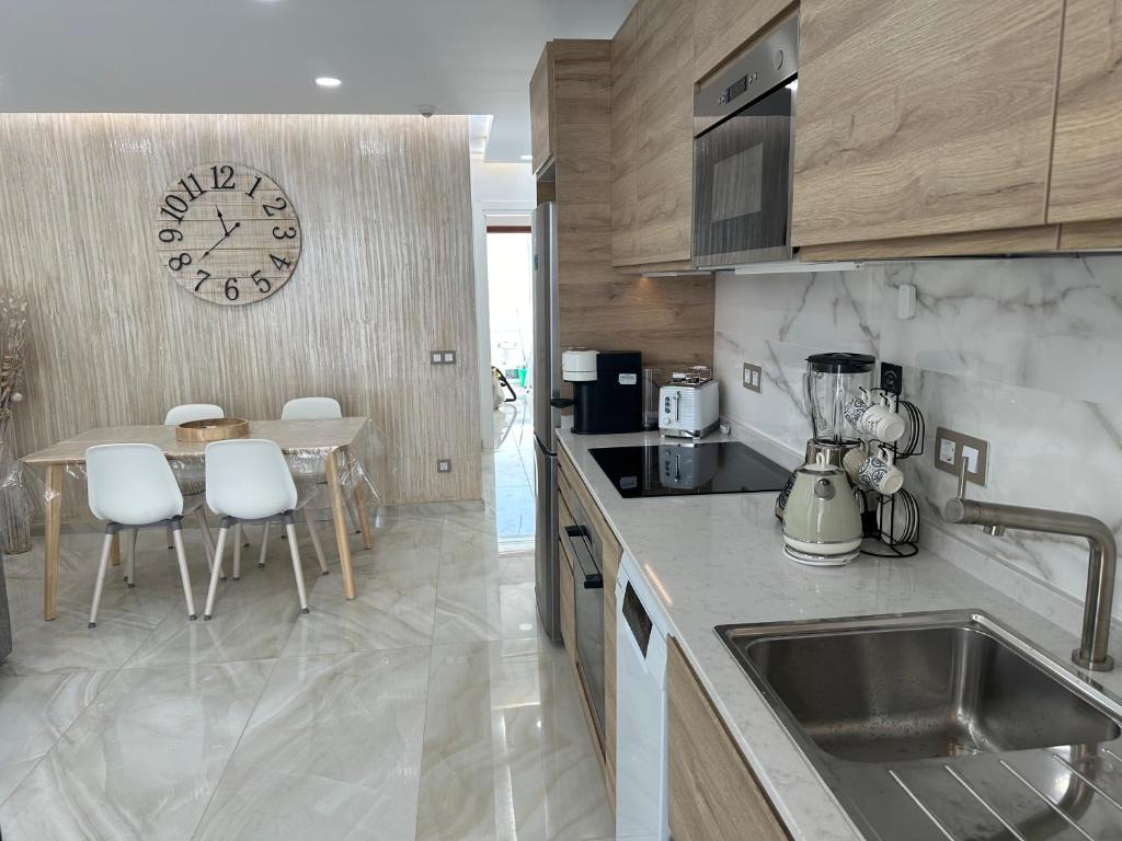 Una cocina con un fregadero y un reloj en la pared. en BAMBOO CHIC APARTMENT PLAYA DEL INGLES, en Playa del Inglés