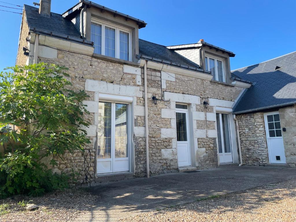 ein altes Steinhaus mit weißen Türen und Fenstern in der Unterkunft Charmante maison tourangelle proche Amboise in Mosnes