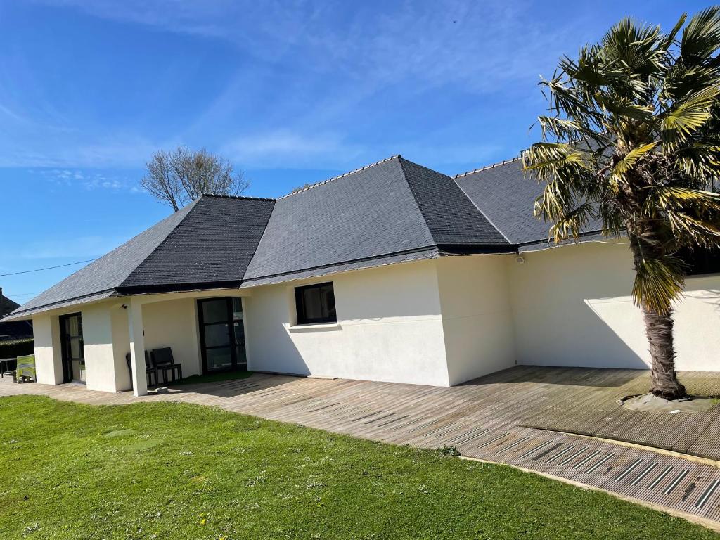 une maison blanche avec un toit noir et un palmier dans l'établissement GÎTE PMR Morbihan, à Locmaria-Grand-Champ