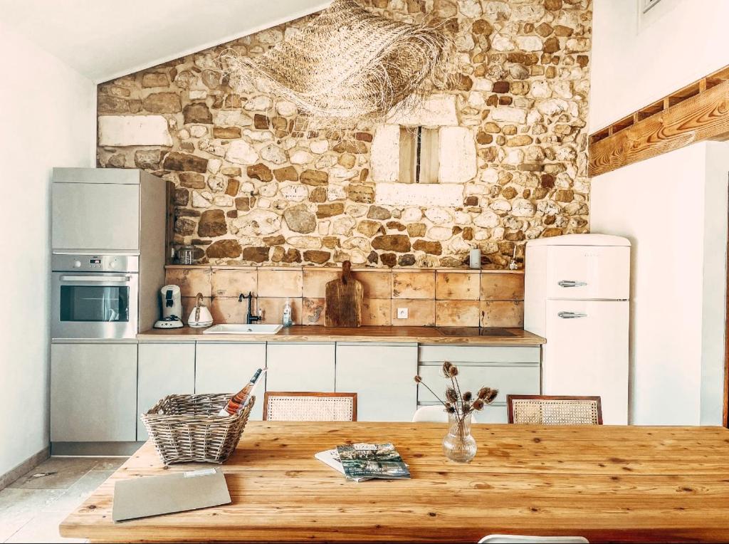 - une cuisine avec une table en bois et un mur en pierre dans l'établissement Gîte dans un domaine - La belle époque- Uzès - 6 personnes, à Baron