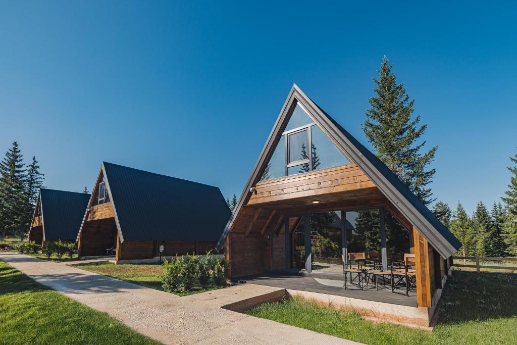 une maison avec un toit à la mansarde et une extension en verre dans l'établissement Mountain Homes Durmitor 1, à Žabljak