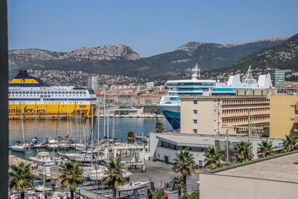 un navire de croisière amarré dans un port planté de palmiers dans l'établissement Charmant T3 au Mourillon, à Toulon