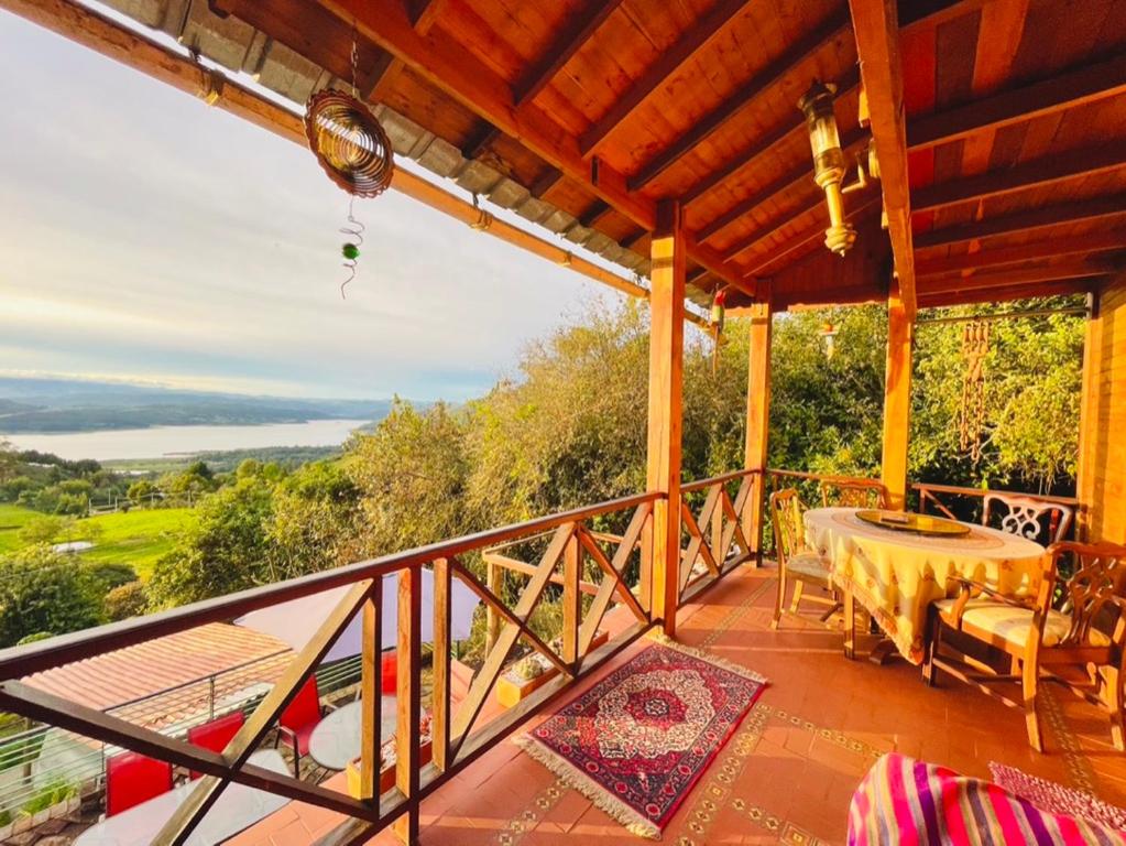 a balcony of a house with a table and chairs at Varsovia, casa de madera biblioteca in Guatavita