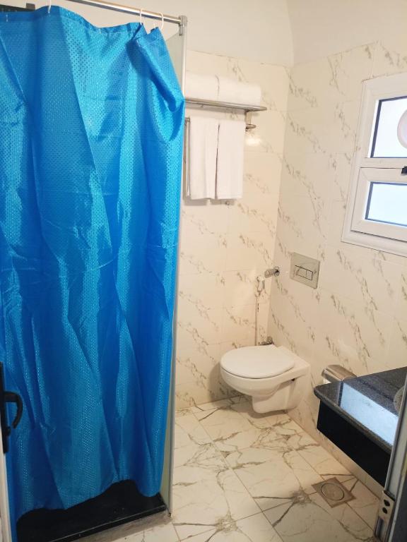 e bagno con servizi igienici e tenda doccia blu. di Dolphin Continental Hotel a Quseir