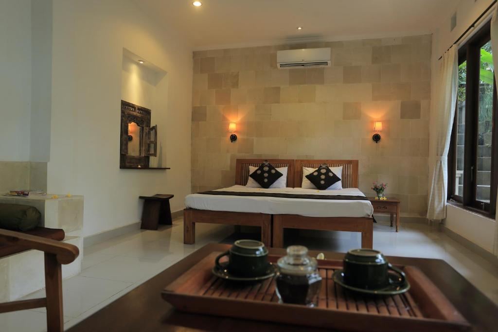 a bedroom with a bed and a table with a tray at Suastika Guest House in Ubud