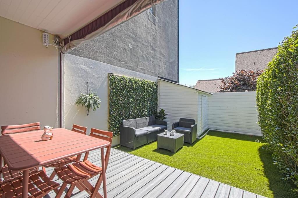 d'une terrasse avec une table en bois, des chaises et de la pelouse. dans l'établissement Secret Garden joli cottage rénové proche mer, à Blonville-sur-Mer