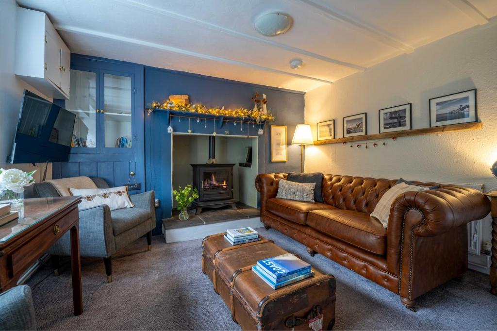 a living room with a leather couch and a fireplace at Charming coastal cottage with stunning views - Hope Cottage in Mortehoe
