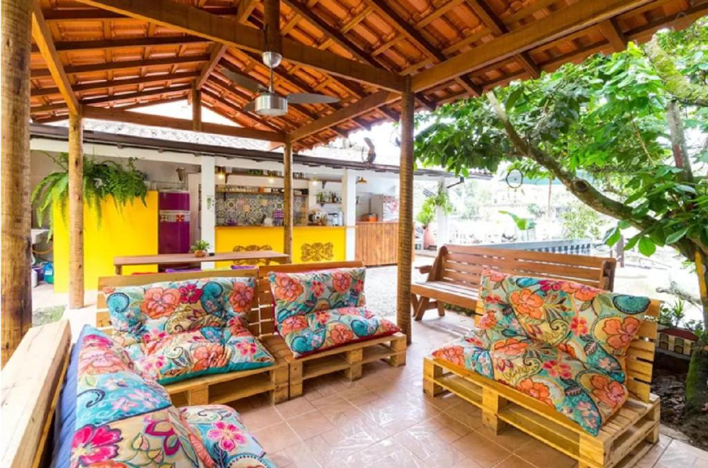 une terrasse avec deux canapés, une table et des bancs dans l'établissement Maracujá Hostel, à Parati