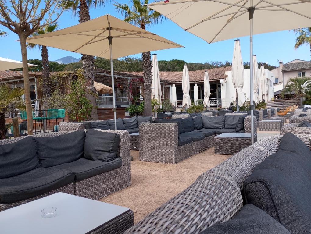 eine Terrasse mit Sofas und Sonnenschirmen in der Unterkunft belles chambres toutes équipées bord de mer gérance nouvelle in San-Nicolao