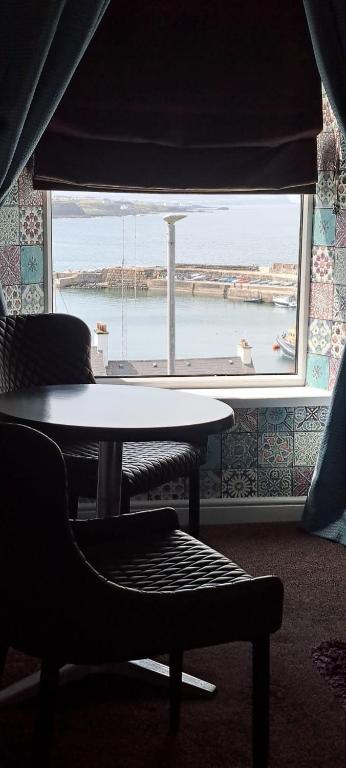 a table and a chair in a room with a window at Avarest House BB Adults Only in Portrush