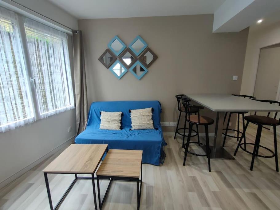 un salon avec un canapé bleu et une table dans l'établissement Appartement central Villedieu, à Villedieu-les-Poêles