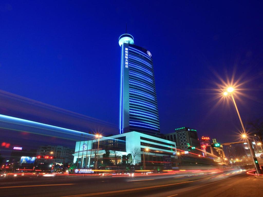 a tall building at night with a street and street lights at HJ International Hotel - Free shuttle bus to Canton Fair during exhibition period in Dongguan