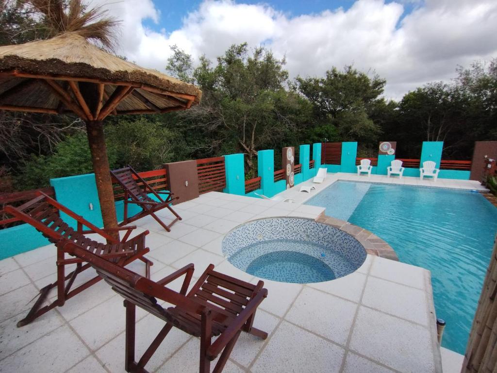 a pool with chairs and an umbrella and a table and chairs at A Mi Manera Apart in Merlo