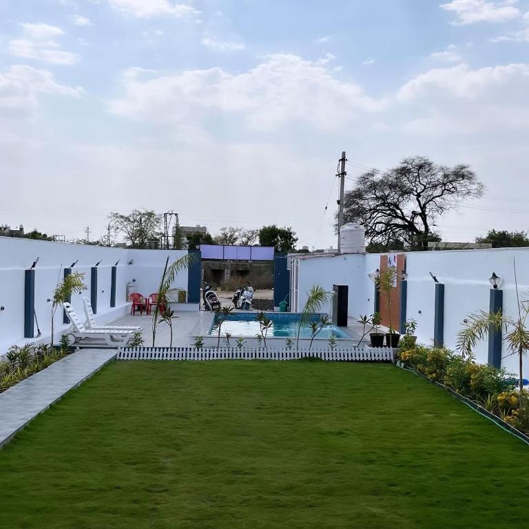 a backyard with a lawn and a white building at Casa bella a beautiful house in Chittaurgarh