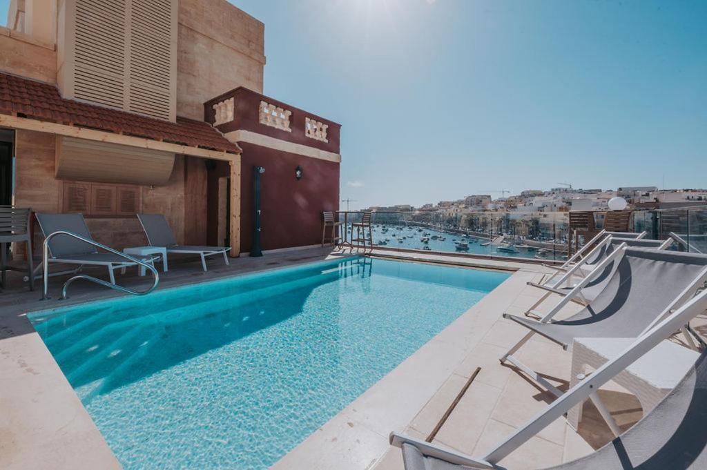 a swimming pool with chairs on a building at Casa Rosanna Malta B&B Adults only 16 plus in Marsaskala