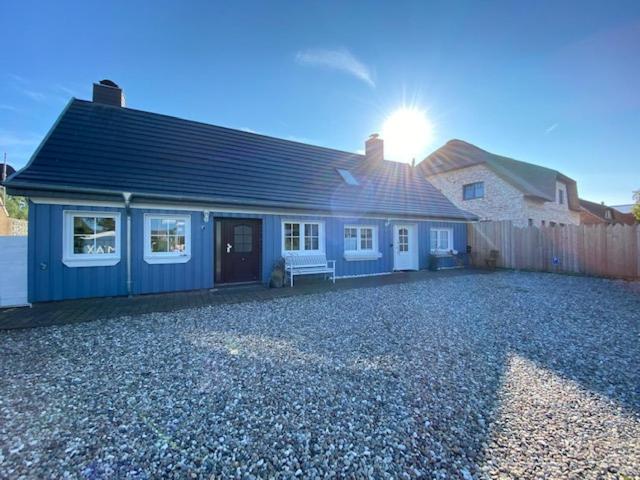 ein blaues Haus, hinter dem die Sonne scheint in der Unterkunft Little Blue Cottage #7 in Fehmarn
