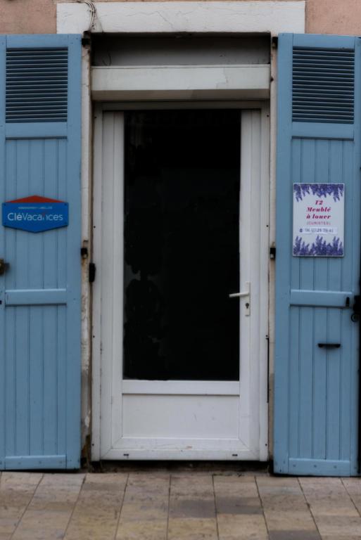 une porte dans un bâtiment avec un panneau sur celui-ci dans l'établissement les volets bleus, à Lamalou-les-Bains