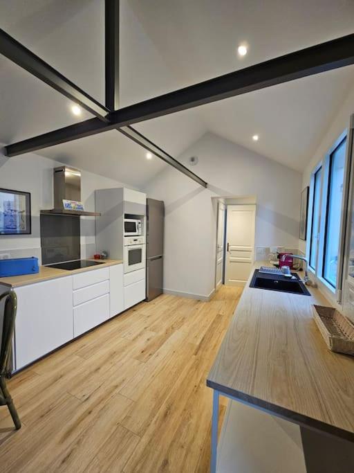 Il comprend une grande cuisine avec des placards blancs et du parquet. dans l'établissement Maisonnette à Batz sur Mer centre 8min des plages à pieds, à Batz-sur-Mer