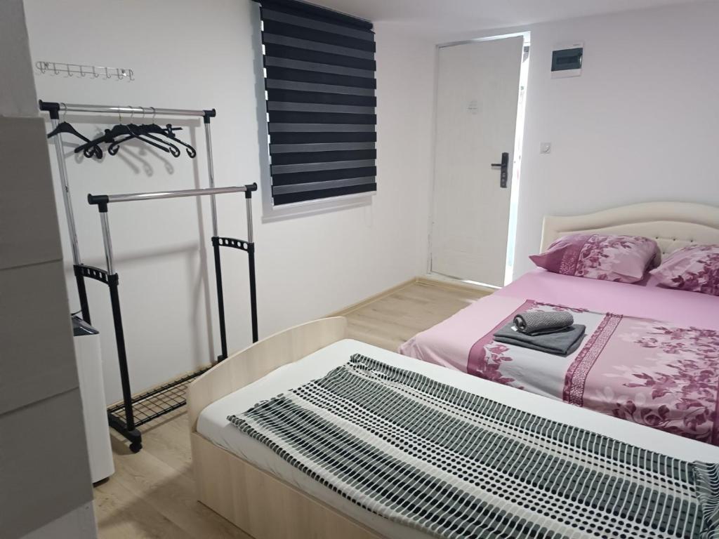 a bedroom with a bed with pink sheets and a window at Apartman Deni in Tuzla