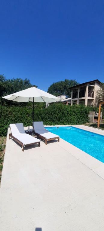 a white umbrella and two lounge chairs next to a swimming pool at La Maru in Villa Giardino