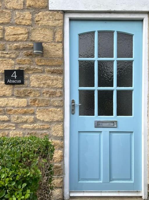 a blue door on a brick building with a sign at Abacus Cottage in Whitwell on the hill