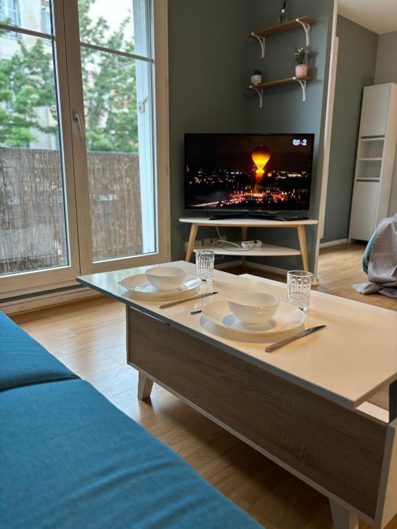 d'un salon avec une table et une télévision. dans l'établissement Studio Bailly, à Bailly-Romainvilliers