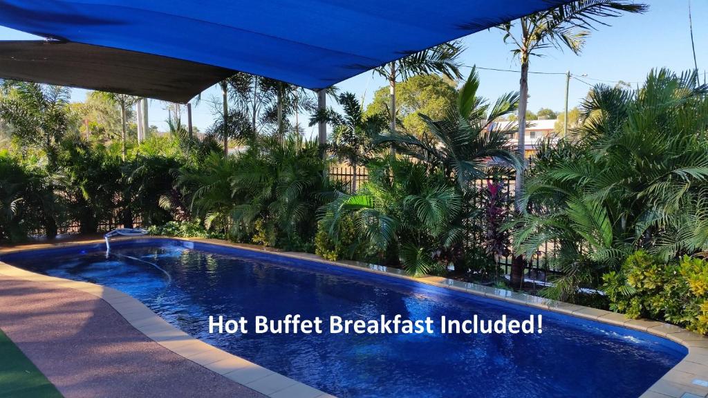 a swimming pool in a resort with a blue umbrella at Leichhardt Accommodation in Mount Isa