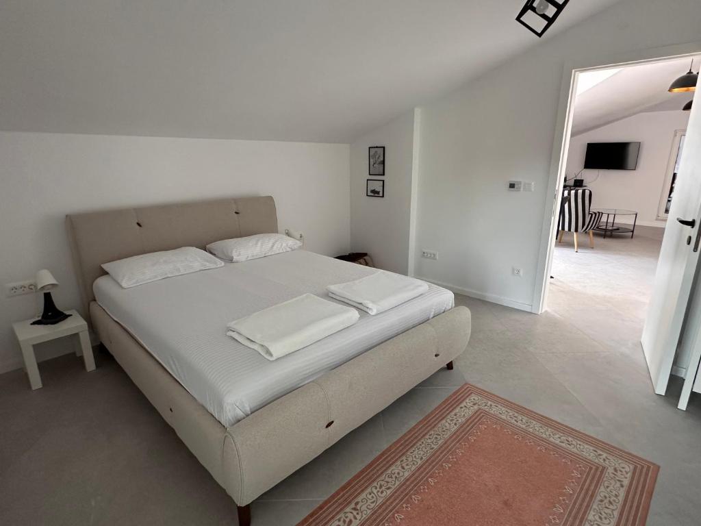 Un dormitorio blanco con una cama con sábanas blancas. en Quince Luxury Apartment, en Ðenovići