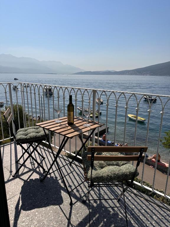 a table and chairs with a bottle of wine on a balcony at Quince Luxury Apartment in Đenovići