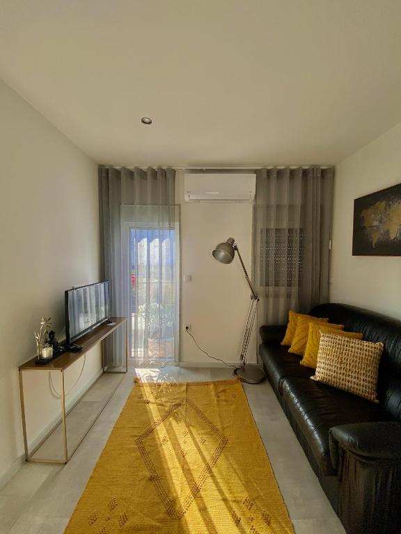 a living room with a black leather couch and a television at Casinha dos Carris in Valença