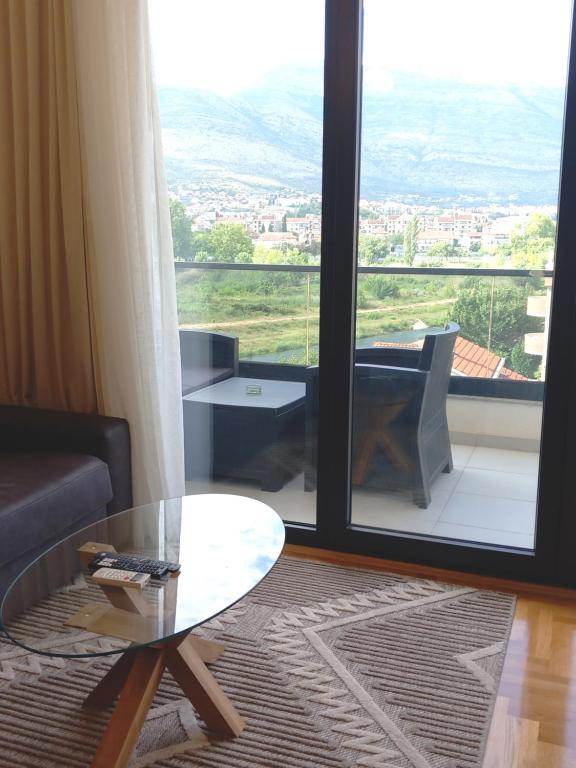 een woonkamer met een glazen tafel en een groot raam bij Apartman 20 in Trebinje