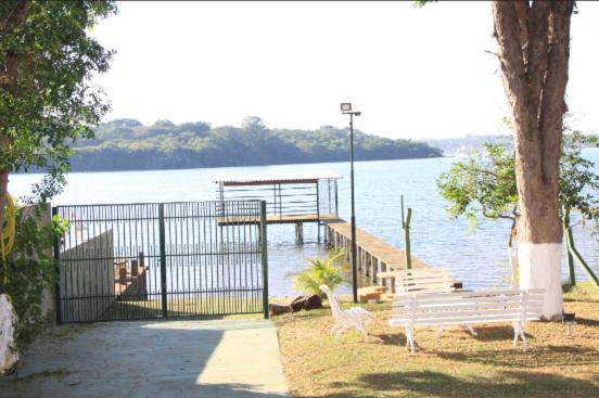 Un muelle con dos bancos al lado del agua en Recanto Boa Ideia, en Campo Alegre