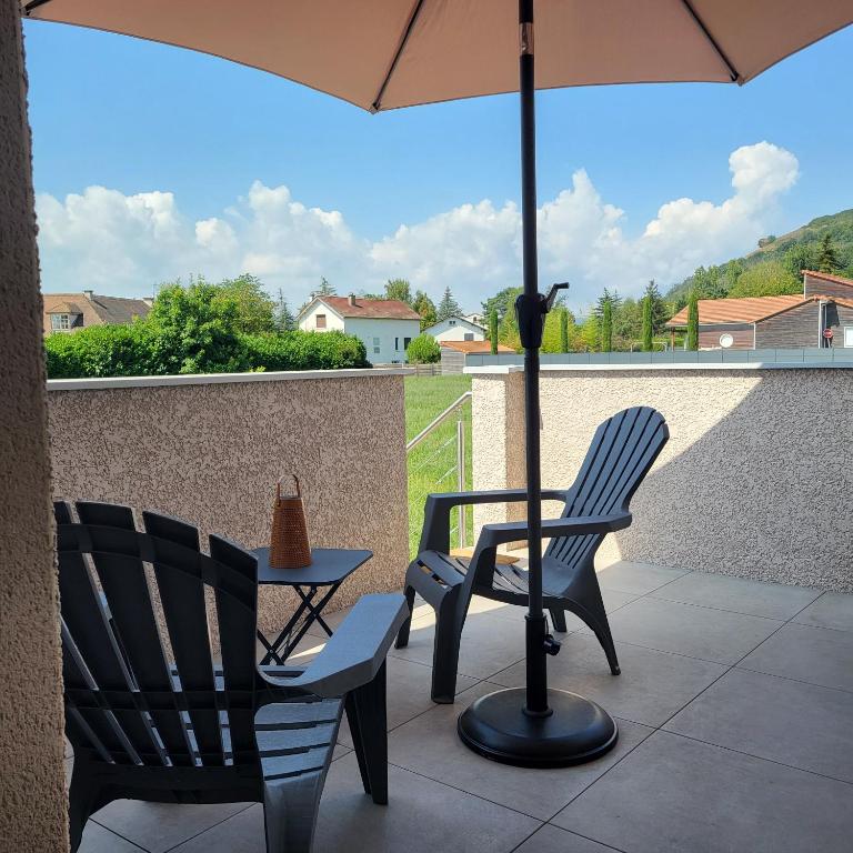 - 2 chaises et un parasol sur la terrasse dans l'établissement Le Nid du Bosquet, à Issoire