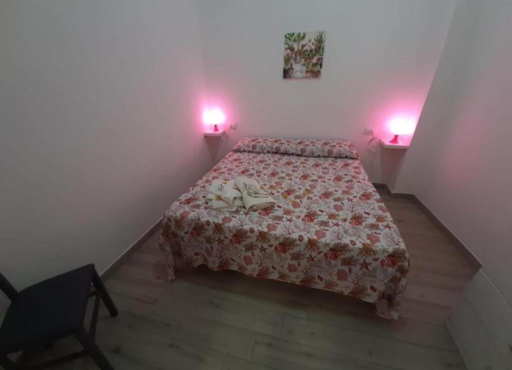 a bedroom with a bed and two lights on the wall at appartamento gioioso in Castellammare del Golfo