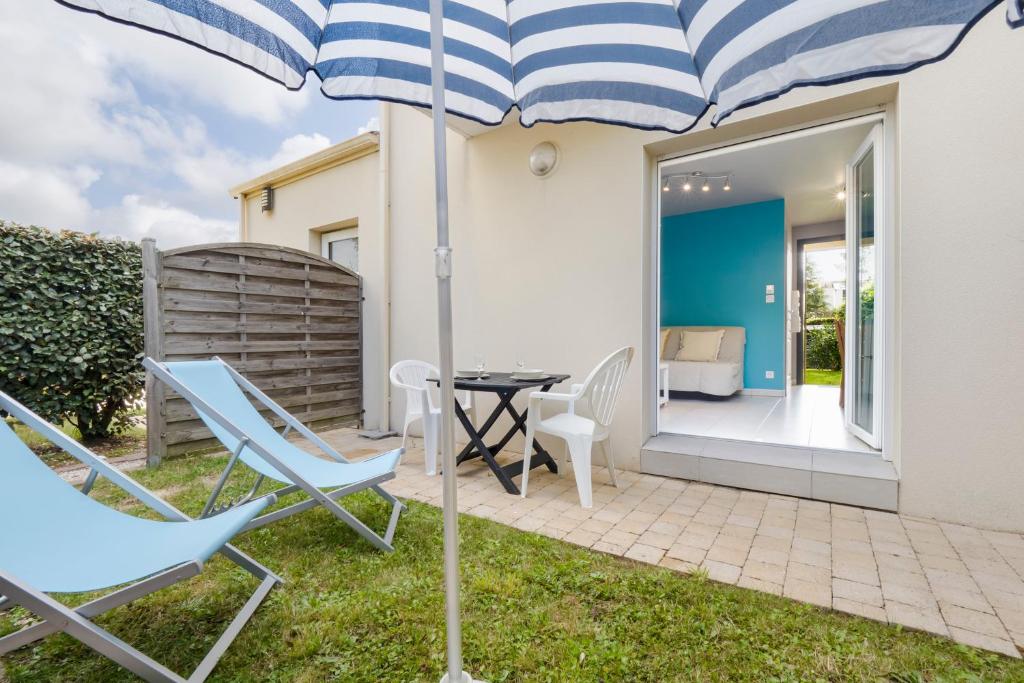 un patio avec des chaises, une table et un parasol dans l'établissement Studio 1 Cap Ouest Vacances, à Pornichet