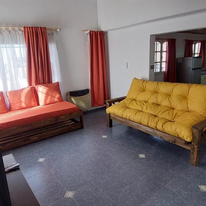 a living room with a yellow couch and red curtains at Casa bosque de Sol in Malargüe
