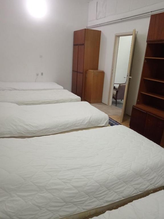 una camera con tre letti, un comò e uno specchio di City Central a Paraćin