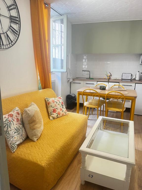 un salon avec un canapé jaune et une table dans l'établissement Cosy Appartement moderne et central !, à Béziers