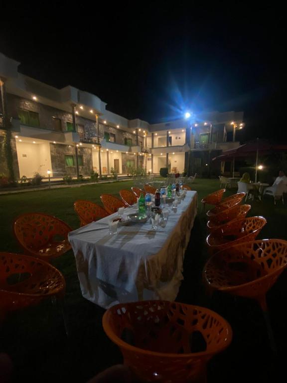 a long table with orange chairs and a white table cloth at Hotel Blangsa Indus View in Skardu