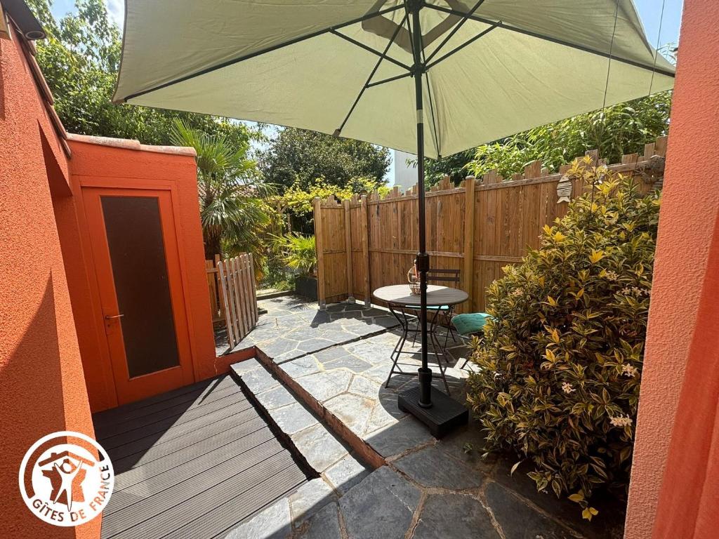 un patio avec une table et un parasol dans l'établissement Gîte rénové proche plage, centre-ville et pistes cyclables avec terrasse privative - FR-1-426-560, à Les Sables-dʼOlonne